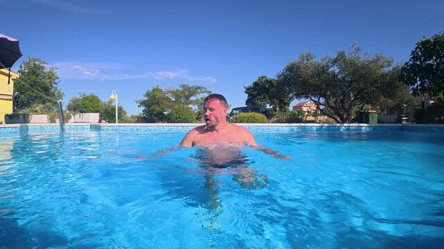Man emerging from underwater in a swimming pool captured in 120 FPS slow motion, creating a cinematic summer scene with splashing water and refreshing atmosphere.