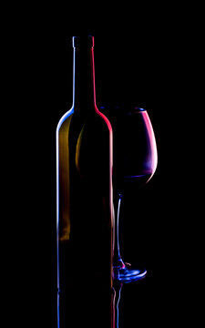 Still life with a glass of wine and a bottle on a black background