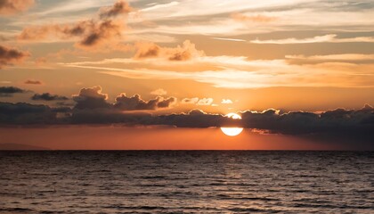 Obraz premium Stunning golden sunset over the ocean with clouds on the horizon