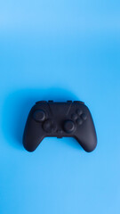 Vertical flat lay of black wireless gamepad on blue background with copy space. Perfect for social media gaming ads.  © wibiwisnu