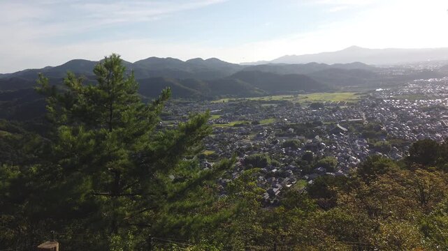 Panoramic aerial of Kyoto city seen from the hills of Arashiyama in Japan, overlooking the urban landscape with surrounding mountains and the famous Arashiyama district in the fore