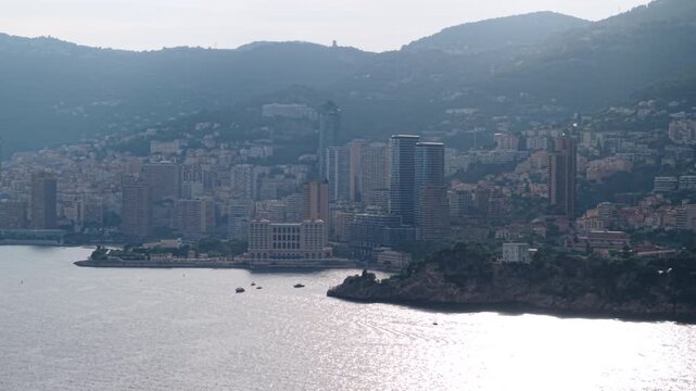 Drone pans across Monaco skyline and Monte-Carlo Bay Hotel above sunlit sea.