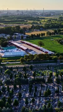 Plock industrial complex with recyclable parts rises beyond fields, trees and transport facilities in Poland