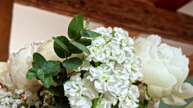 Lovely bouquet of fresh white flowers, including peonies and matthiola, wrapped in paper