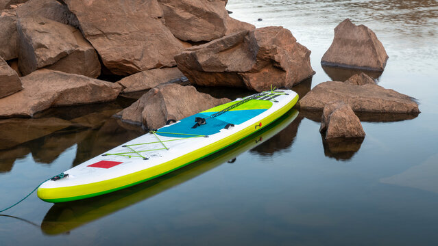 inflatable stand up paddleboard on a rocky shore of mountain lake - Horsetooth Reservoir in northern Colorado in fall scenery