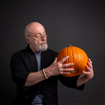 portrait of senior, bearded man with a pumpkin. Thanksgiving or Halloween greeting card concept