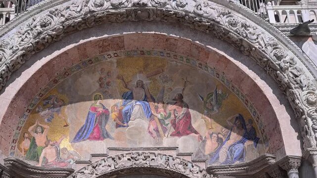 Colorful Christ in Majesty mosaic crowns the main west portal of St Mark's Basilica, framed by carved stone arch detail.