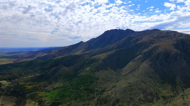Broad drone panorama showcases the dramatic Ventania ridge rising above fertile plains and native mountain vegetation.