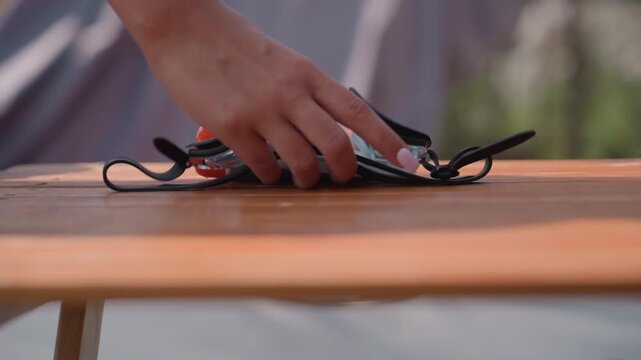Woman handles pair of black swimming goggles placing them on wooden surface. focuses on her hands and goggle details with soft natural light illuminating scene