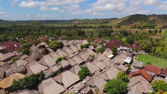 Sade Traditional Village in Lombok surrounded by tropical hills and farmland, aerial backdrop establishing cultural landmark