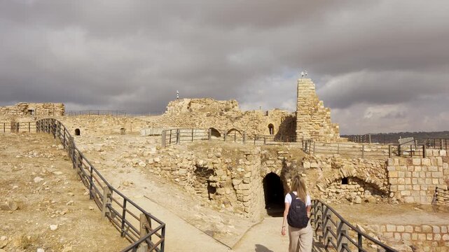 Female tourist sightseeing at medieval Kerak Castle ruins above Al-Karak, Jordan, showing historic stone fortifications architecture, 4k handheld