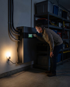 Homeowner reading a glowing charge display on a home battery backup unit at night