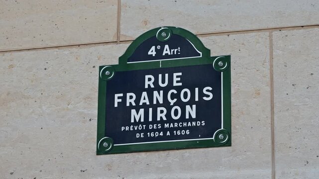 Green and white Rue Fran&ccedil;ois Miron street sign on a beige stone wall in the 4th arrondissement, static close-up shot.