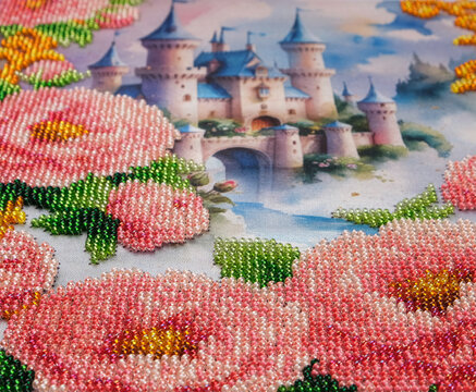 Fantasy artwork depicts a romantic castle with blue towers framed by pink bead embroidered flowers and golden ornaments, combining fairytale scenery with detailed handmade craft.
