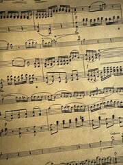 Fototapeta premium Close up of aged sheet music with musical notes and textured paper. Music notes Sheet on Aged Paper, black notes on brown paper, musical score, sheet music, musical notation, classical music 