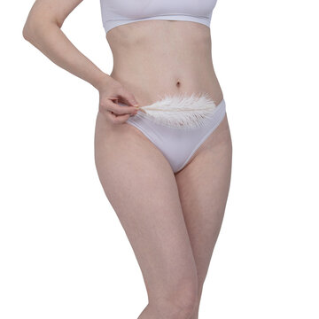 Woman holding soft white feather near her bikini line. Smooth skin after depilation and hair removal concept. Body care, grooming routine, and gentle skincare beauty treatment