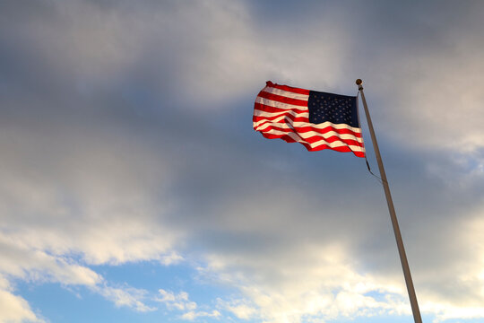 American flag waving on white pole against clear blue sky