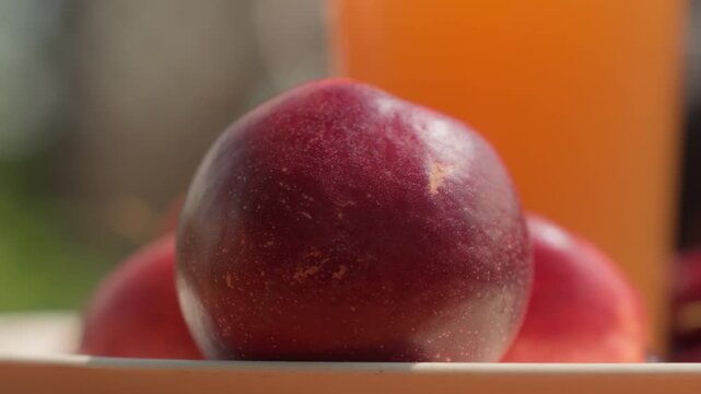 Close up of ripe red apple resting on other fruit with soft lighting and shallow depth of field. smooth glossy skin texture is highlighted by natural light creating subtle shadows that