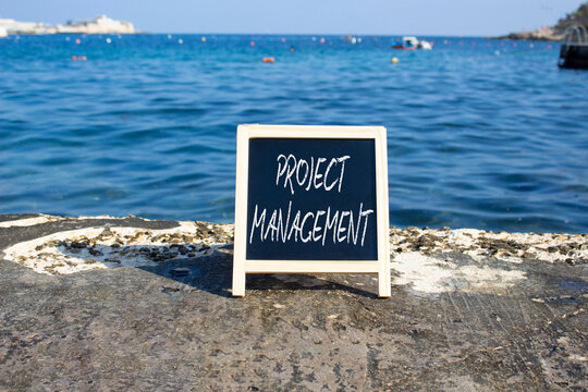 Project Management symbol. White blackboard with Concept words Project Management. Beautiful sea background. Business and Project Management concept. Copy space.