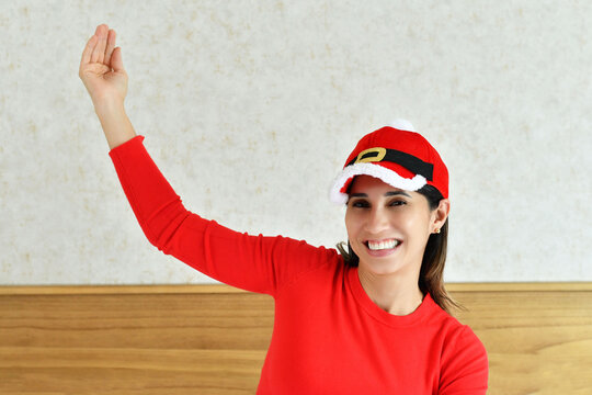 Mujer joven sonriendo, vestida con una blusa roja y una gorra navide&ntilde;a.