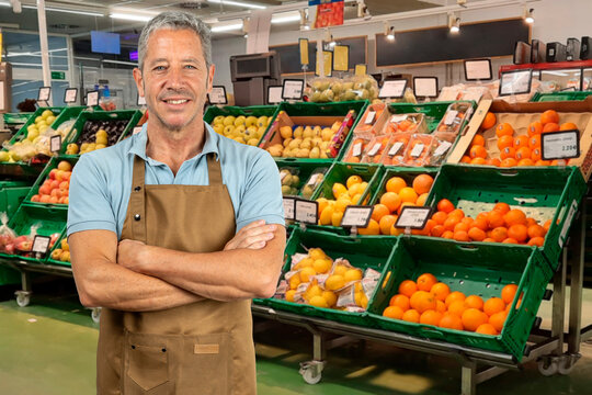 Smiling greengrocer with crossed arms in a fruit shop