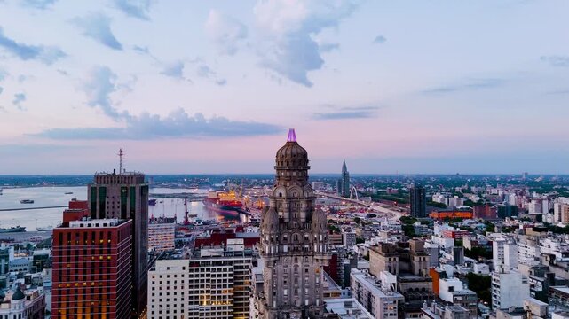 Aerial view of Palacio Salvo and Plaza Independencia in Montevideo, Uruguay, with the harbour, city buildings and pastel sky at twilight.