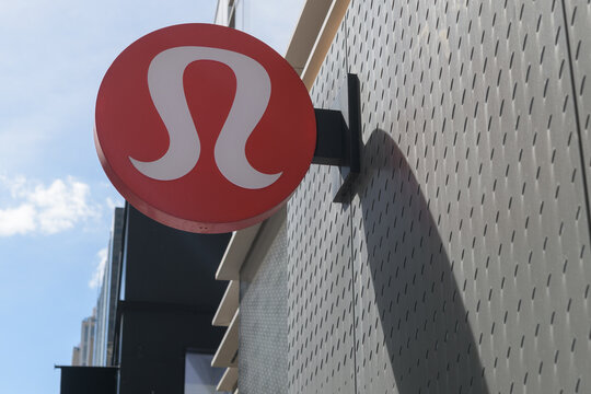 wall mounted round projecting logo sign outside lululemon, a sportswear store, located here at 2 Bloor St W, Toronto