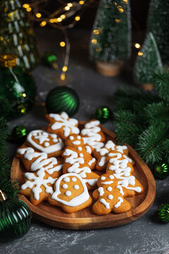 Christmas gingerbread cookies decorated with white icing on a wooden plate with festive decorations