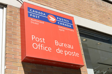 Fototapeta premium box sign of Canada Post, Post Office wall-mounted on the exterior of a Shoppers Drug Mart at 388 King St W, Toronto