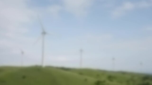 Wind turbines turning on a green hillside under a bright sky, Full Gaussian Blur Abstract