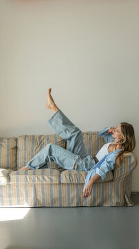 Young woman in casual denim and blue shirt relaxing on a striped couch