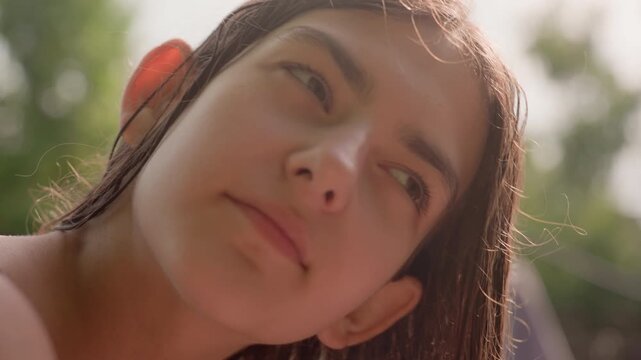 Young woman with wet hair rests peacefully in soft natural light her face and upper body visible from various angles. scene maintains calm atmosphere with consistent outdoor background