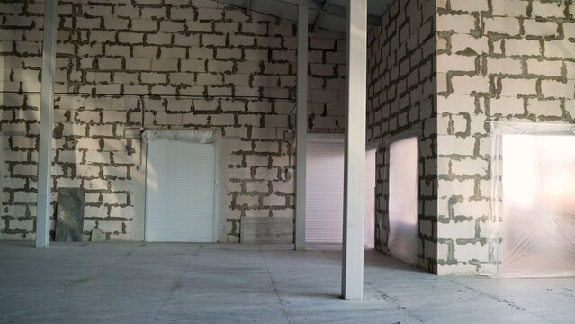Unfinished interior of large industrial building under construction with aerated concrete block walls and concrete floor