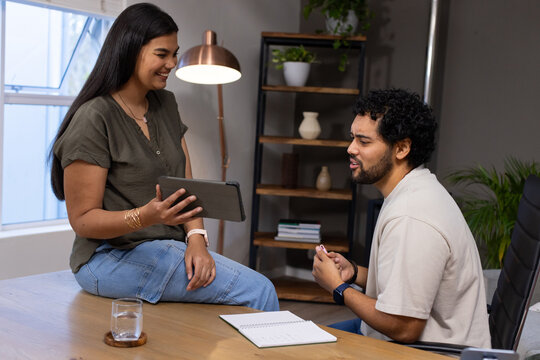 African American coworkers discussing project at office table with tablet, notebook and pen