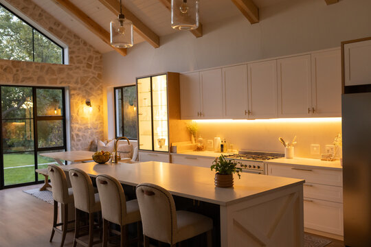 Kitchen island is anchoring farmhouse kitchen with stools, pendant lights and integrated sink