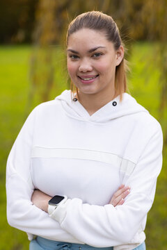 African American woman standing arms crossed in park wearing white hoodie smartwatch on left wrist