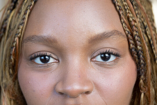 African woman looking at camera in studio, showing braided hair and eye catchlights