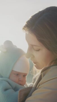 Gentle maternal affection in warm sunlight, Intimate scene of mother softly kissing her sleeping infant in sunshine