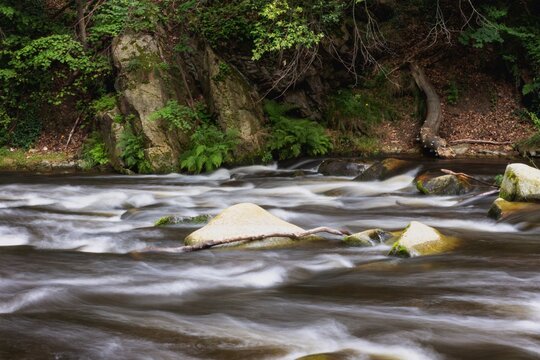 Long-exposure photo of the wild course of the Bode River in the Harz natural forest.