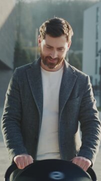 Cheerful dad pushes pram in sunny neighborhood, Gentle father enjoying walk along bright residential street