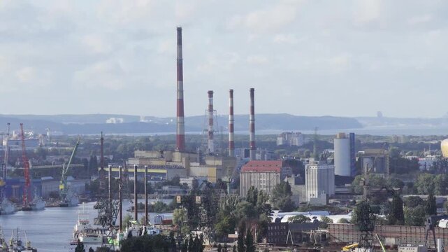 Aerial view of industrial harbor and chimneys with cranes and ships along the river in Gdansk, Pomeranian Voivodeship, Poland.