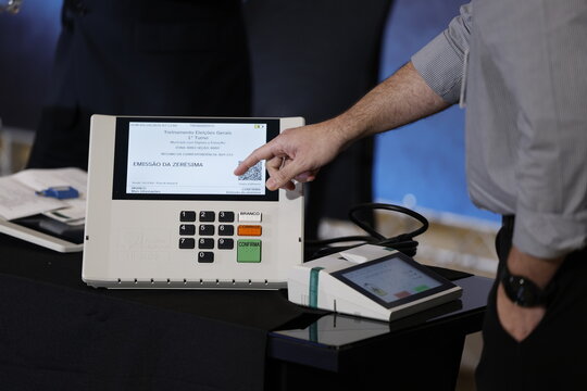Close-up of a Brazilian voter pressing a button on an electronic voting machine at a polling station during the 2026 Brazilian elections, illustrating electronic voting, democracy, civic participation