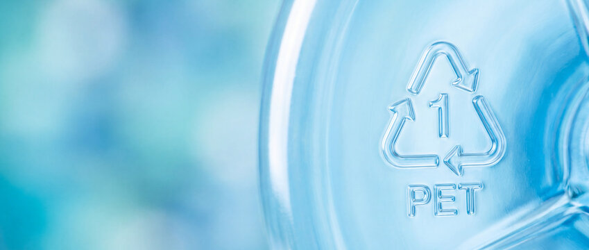 Recycling symbol embossed on plastic bottle with number one pet code on soft blue bokeh background, ideal for sustainable packaging and eco friendly waste management campaigns