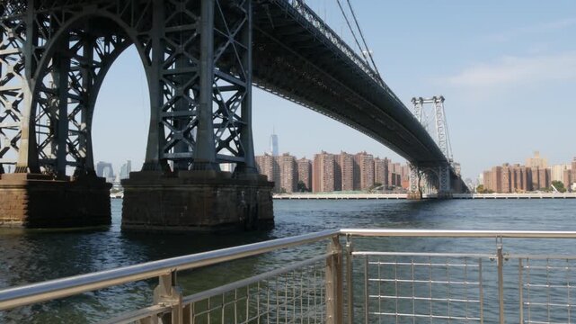 Williamsburg Bridge in Brooklyn, New York City, United States. Transport metallic bridge near Marcy Av subway station and Domino park in Williamsburg. World Trade Center skyscraper tower on Manhattan.