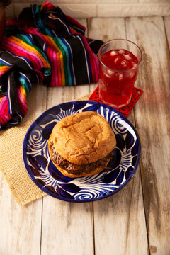 Mexican hojaldra with mole on a rustic clay plate, served with hibiscus water in a traditional setting. Homemade mexican food.