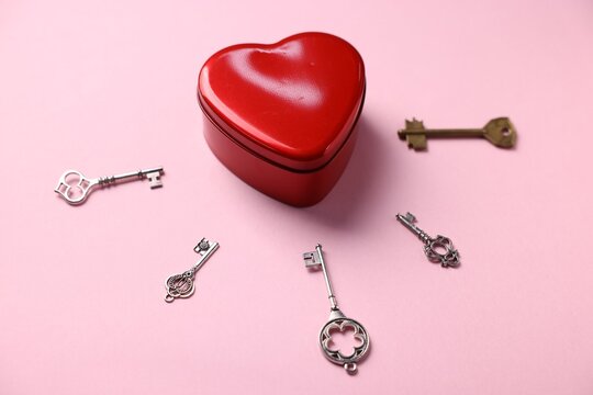 Choice concept. Heart shaped box and different keys on pink background, closeup