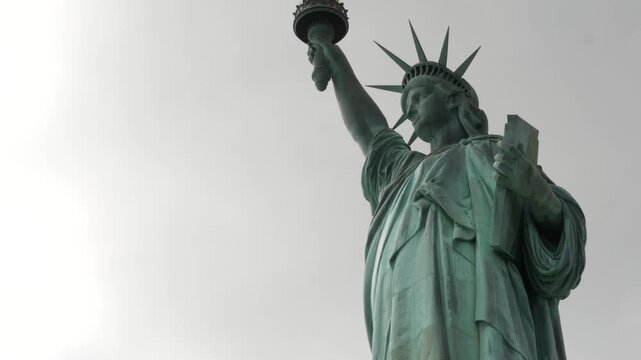 Statue of Liberty on Liberty Island, New York, United States. Blue cooper monument, symbol of democracy and patriotism near Manhattan, NYC USA. Clouds on sky. American independence. Torch and crown.