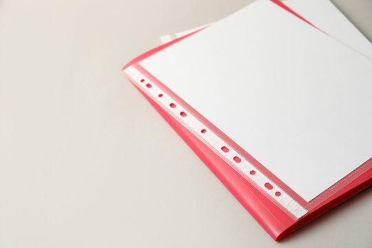 File folder with punched pockets and sheets of paper on light background, closeup. Space for text