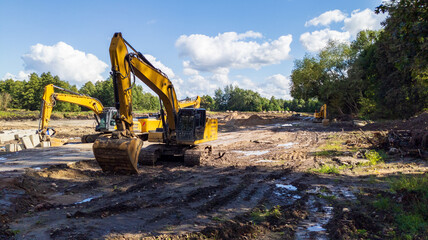 Yellow Excavators Leveling Ground on Construction Site with Heavy Machinery and Blue Sky Background © yaviki