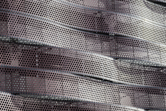 Abstract perforated metal facade with flowing geometric pattern.